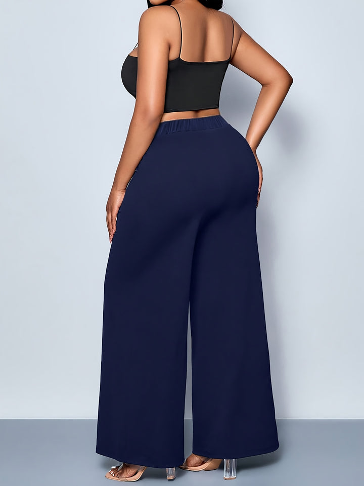 Person wearing a black top and navy wide-leg pants against a light gray background