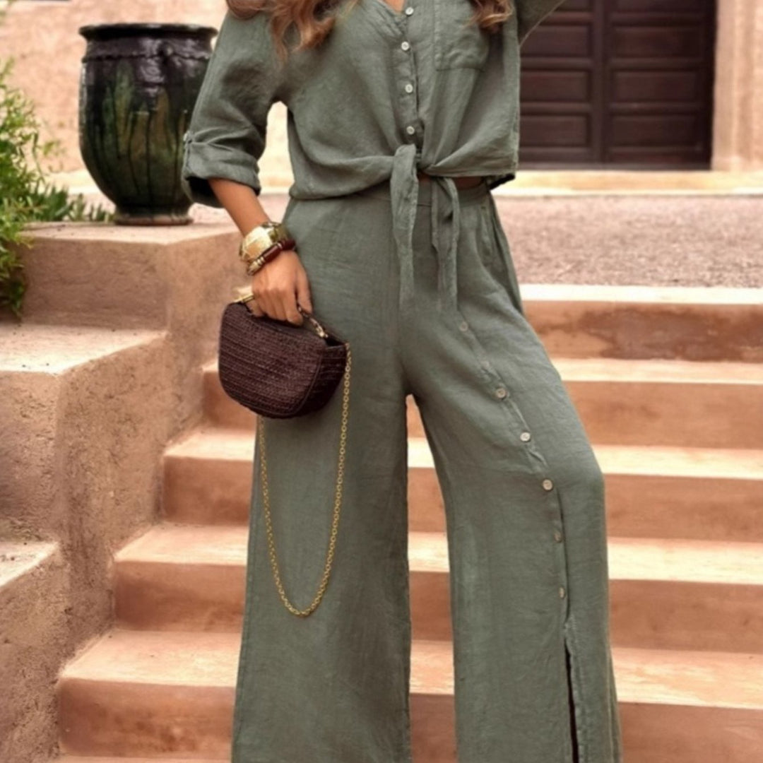 Person wearing a green jumpsuit holding a brown handbag on stone steps.
