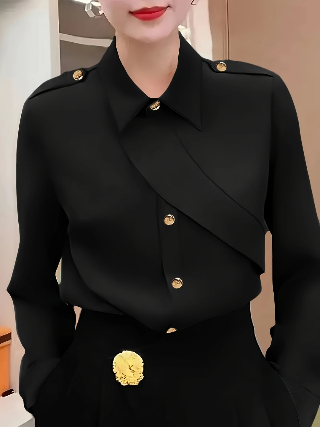Person wearing a black coat with gold buttons and details.