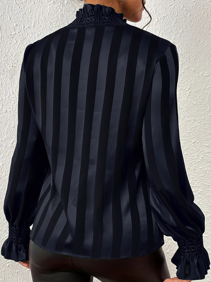Black and gray striped blouse worn by a person against a white wall