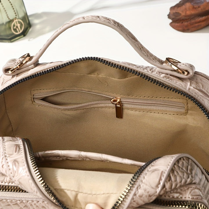 Close-up of a beige handbag with gold zipper and handle.