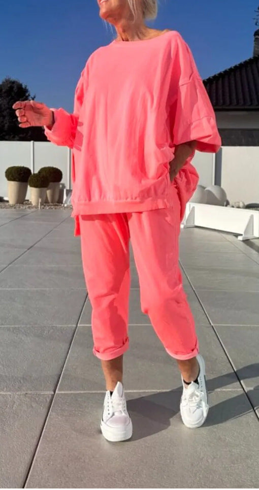 Person wearing a bright pink outfit with white sneakers on a tiled patio.