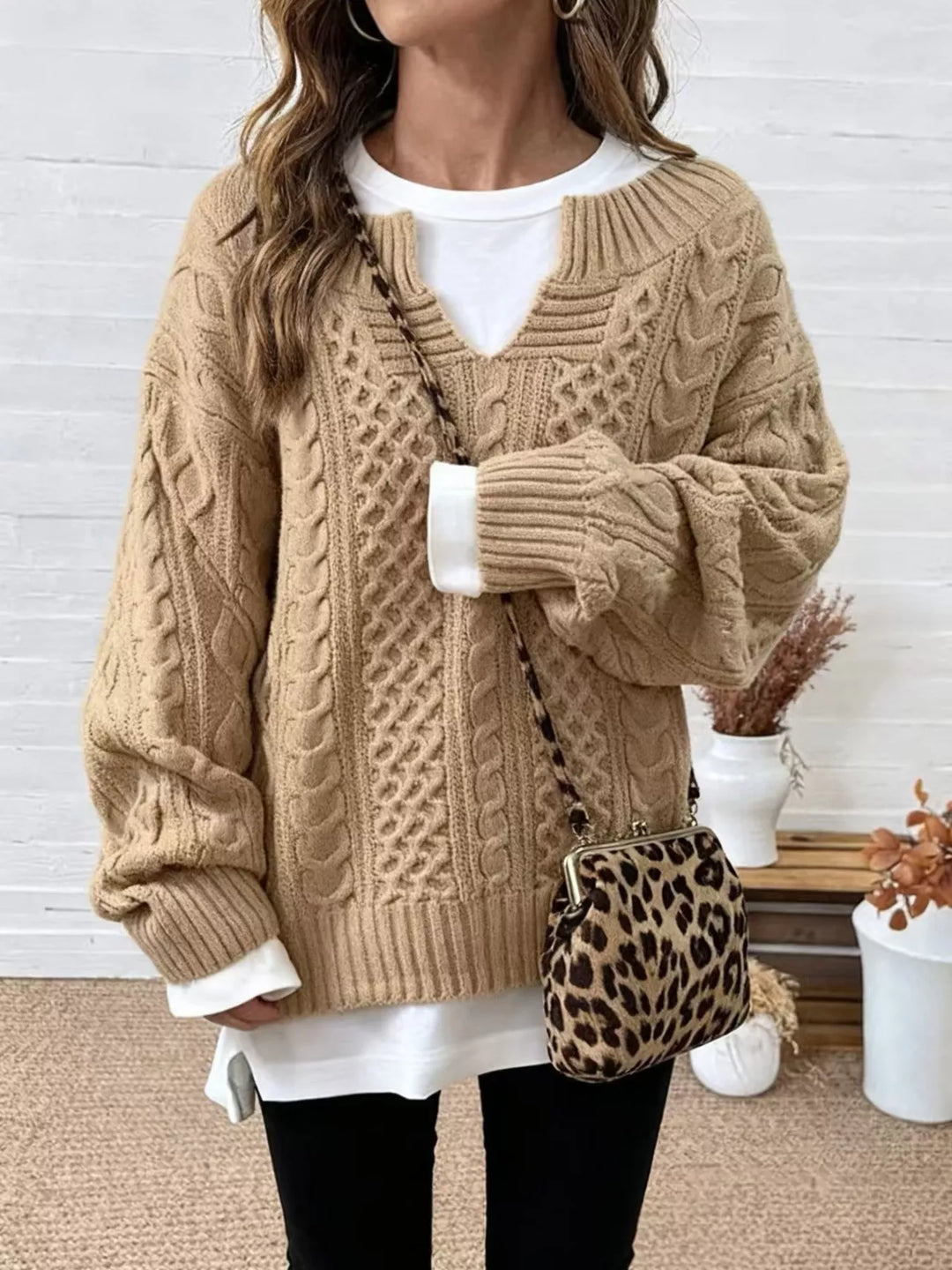 Beige cable-knit dropped-shoulder sweater with V-neck and ribbed cuffs