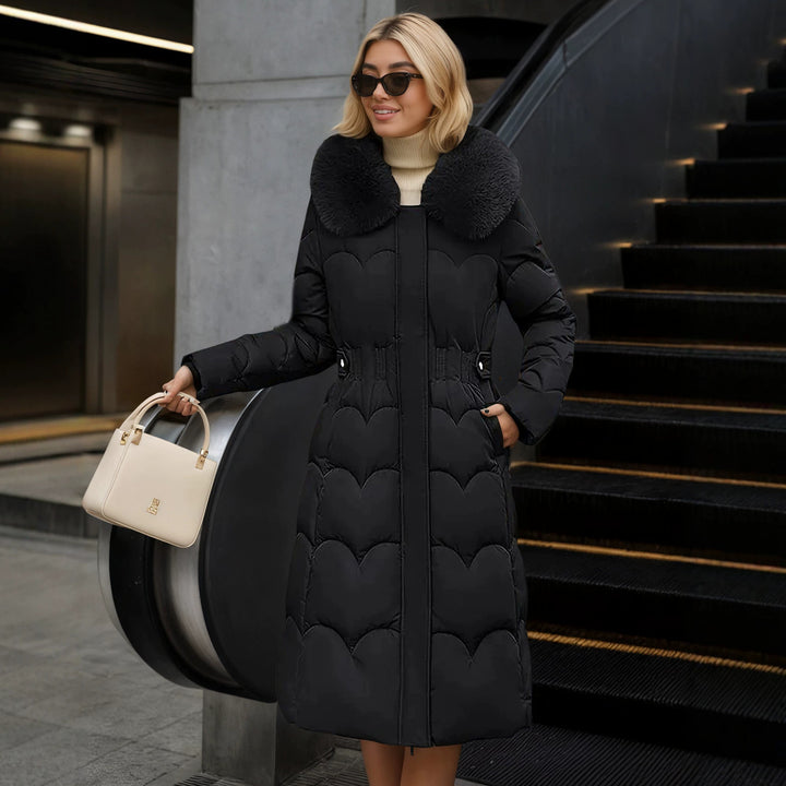Women's Black Long Quilted Coat With Oversized Collar, Front View Beside An Escalator