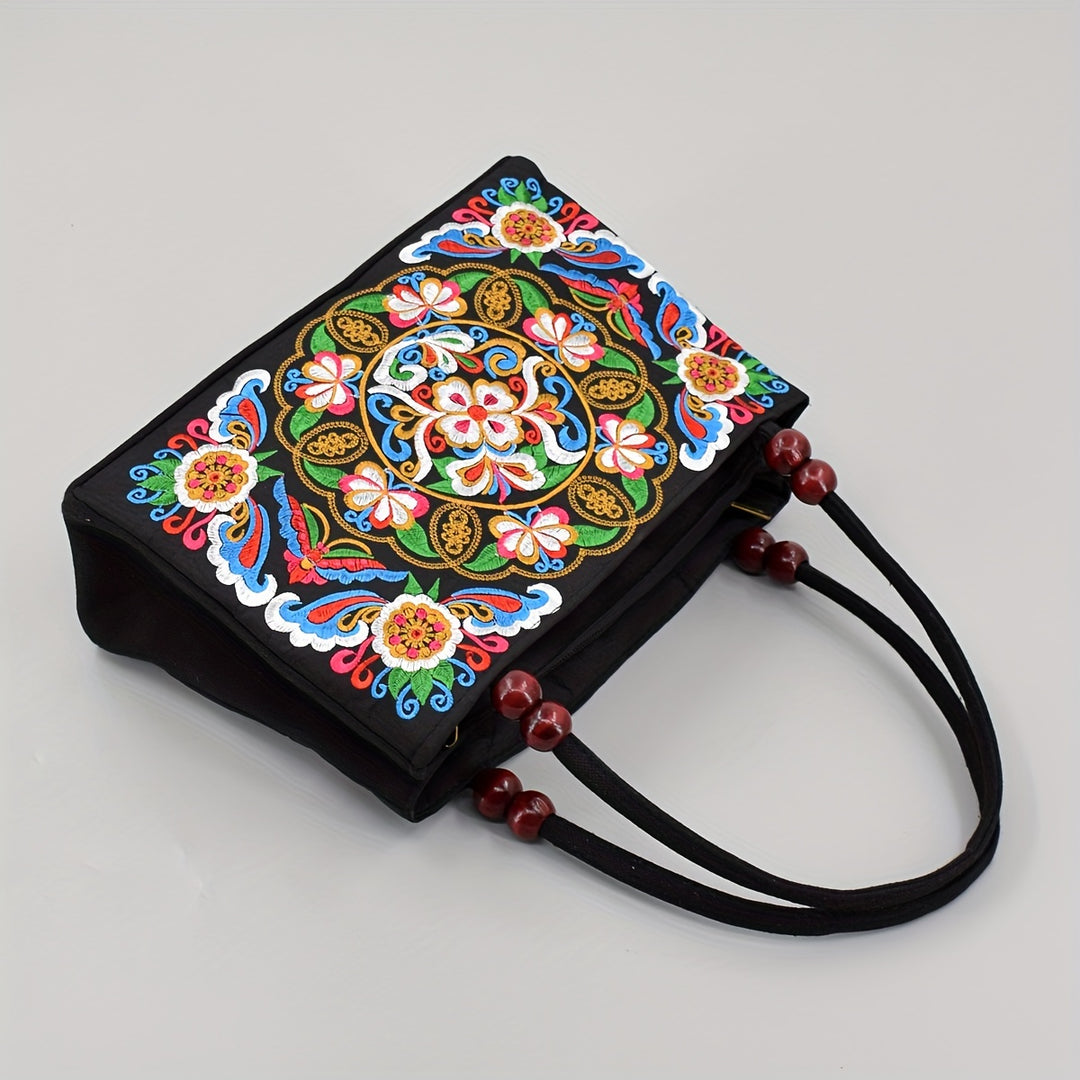 Black handbag with colorful floral embroidery on a gray background