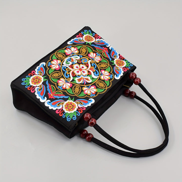 Black handbag with colorful floral embroidery on a gray background