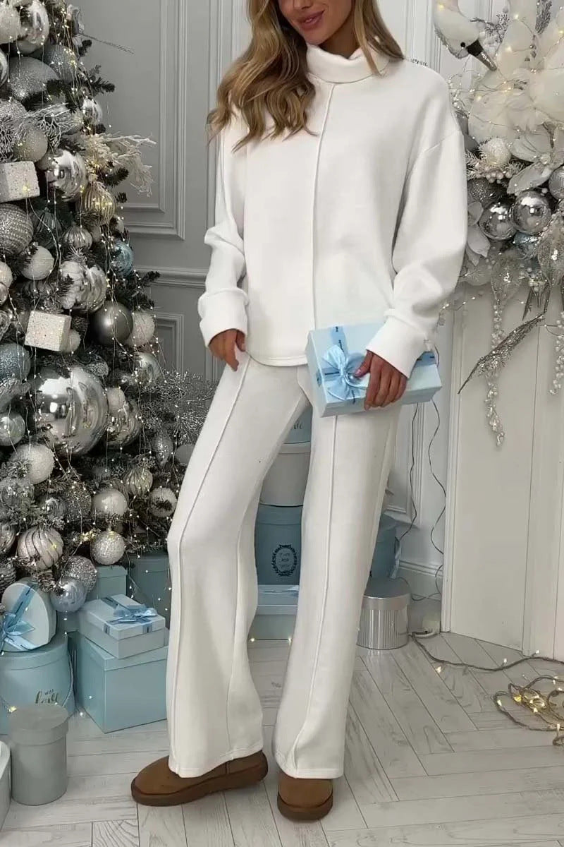 Woman in white outfit standing in a room with decorative Christmas tree and presents.