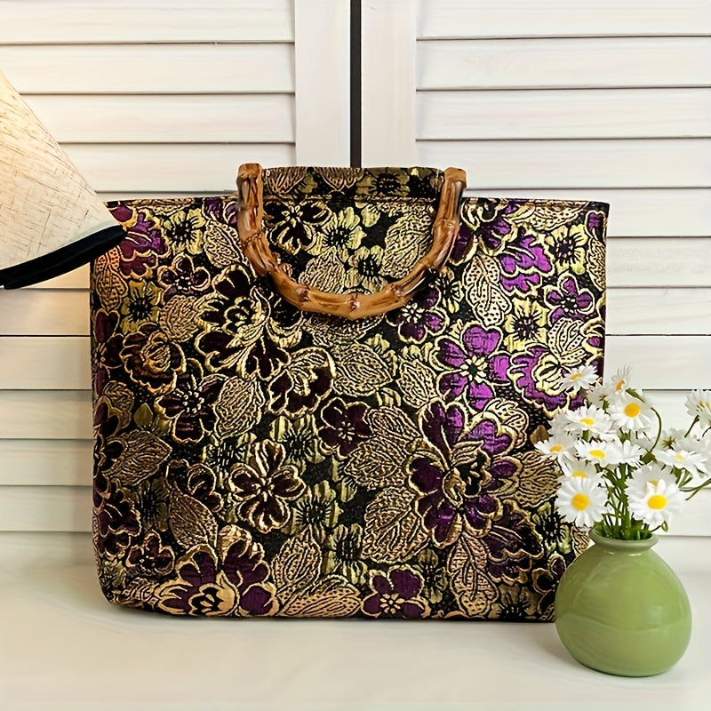 Floral patterned bag with wooden handles on a light wooden surface with a vase of flowers.
