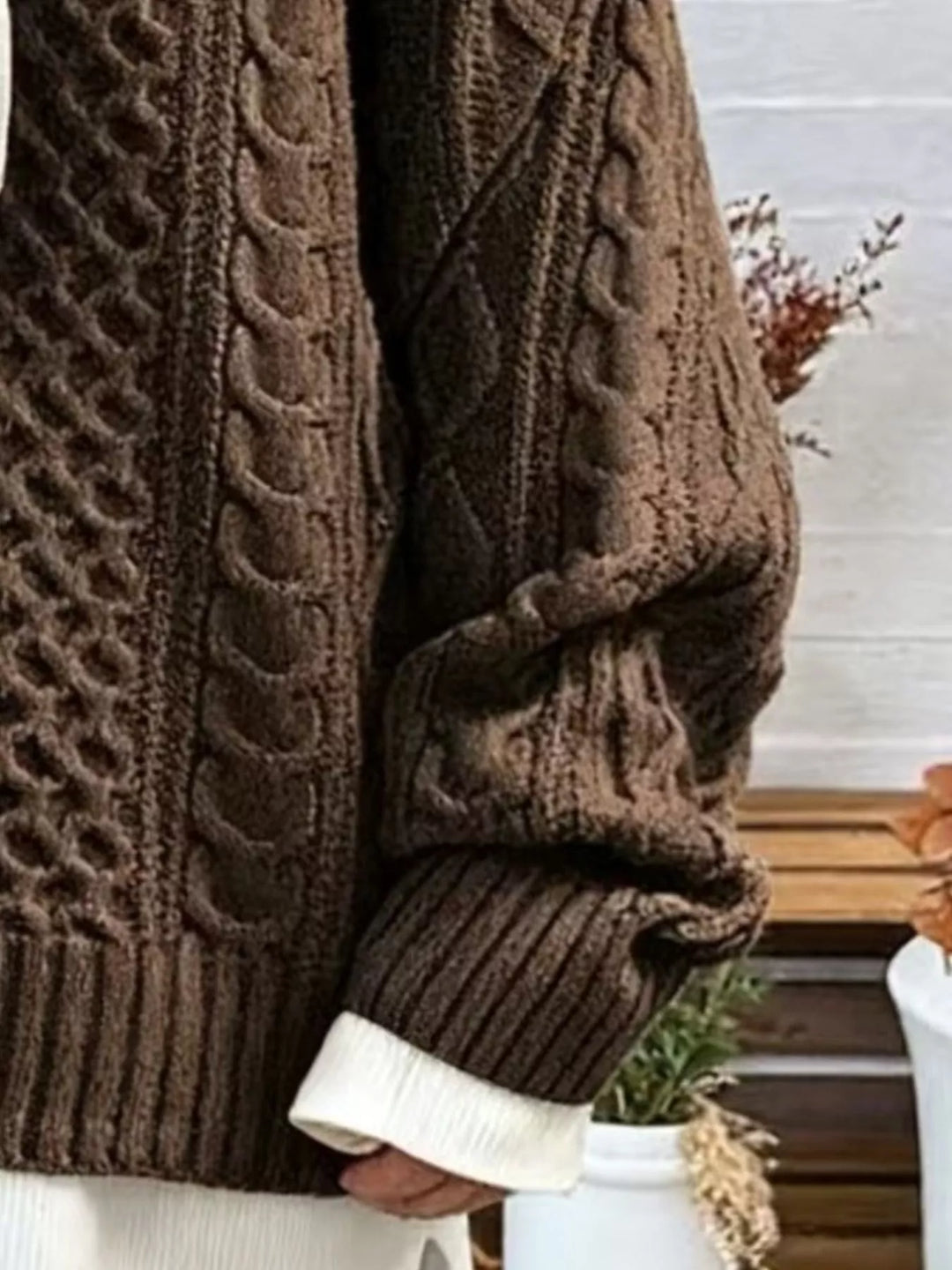 Brown cable-knit sweater sleeve with textured pattern and ribbed cuff detail