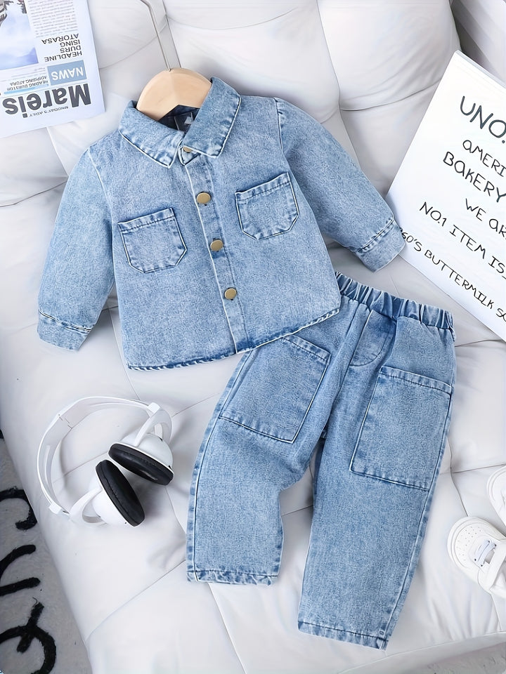 Children's denim jacket and pants set on a white surface with a newspaper and sign in the background.