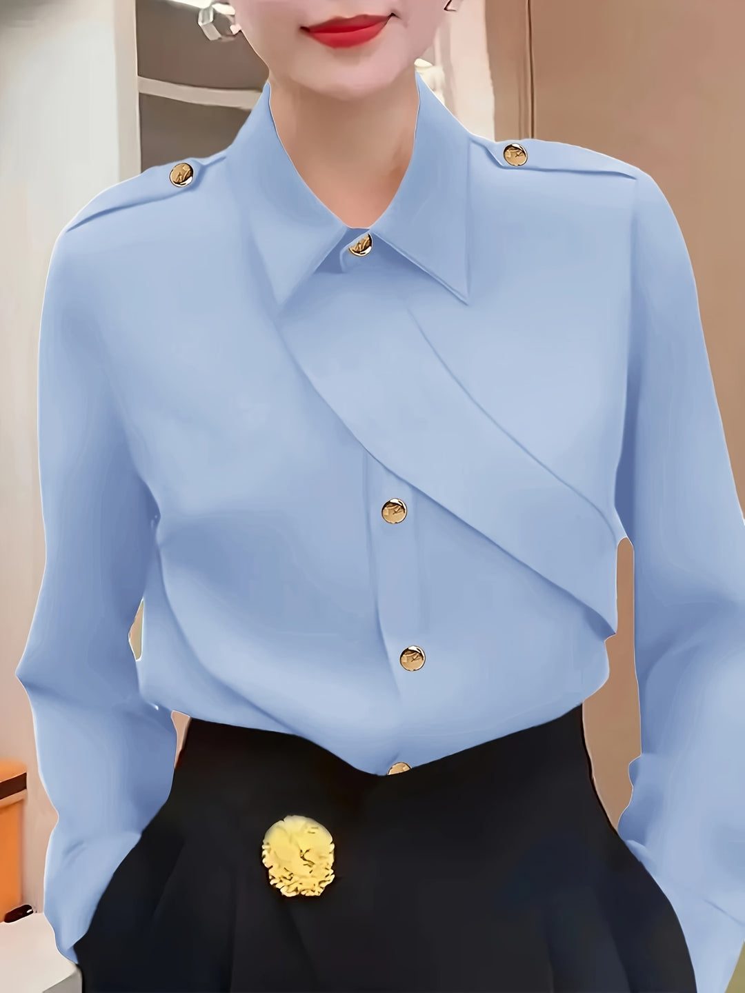 Light blue blouse with gold buttons and black pants worn by a person.