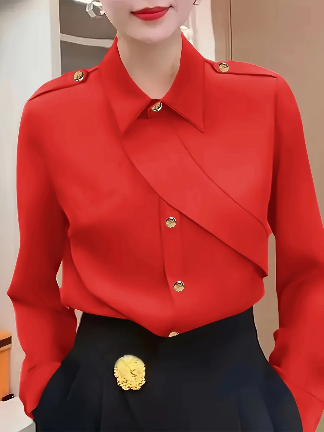Red blouse with gold buttons and black pants worn by a person, with a neutral background.