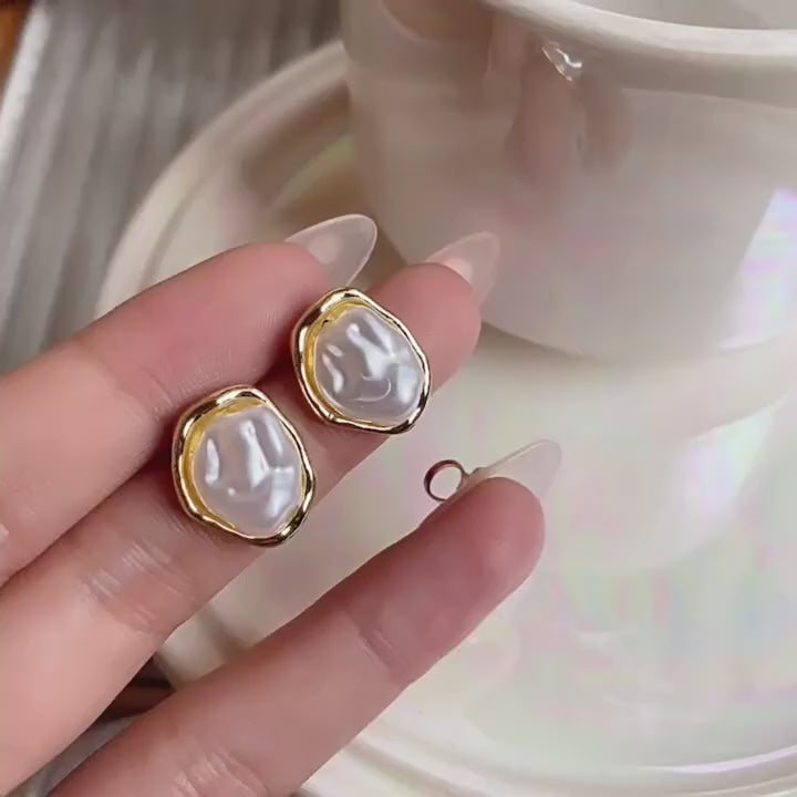 Pearl earring worn by a person on a plain background