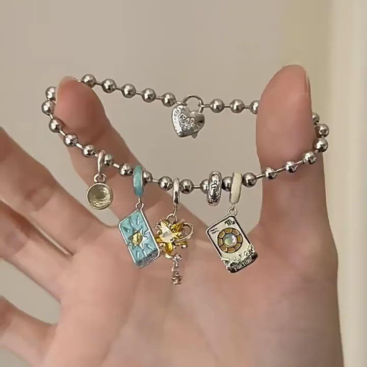 Silver charm bracelet held over a blue jewelry box with star patterns.