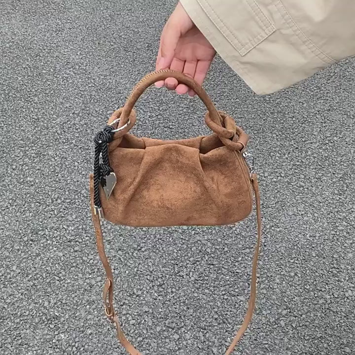 video of Brown suede mini crossbody hobo bag with short handles and black braided charm cord.